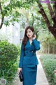 A woman in a blue suit talking on a cell phone.