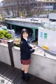 A woman in a school uniform standing on a bridge.