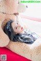 A woman laying on top of a bed next to a teddy bear.