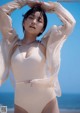 A woman in a white bathing suit standing on a beach.