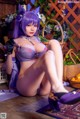 A woman in a purple lingerie sitting on the floor.