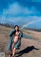 A woman standing in a field with a rainbow in the background.