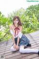 A woman in a school uniform sitting on a wooden deck.