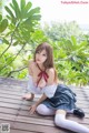 A woman in a school uniform sitting on a wooden deck.