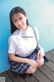 A woman in a school uniform sitting on a wooden floor.