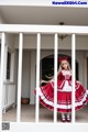 A woman in a red and white dress standing on a porch.