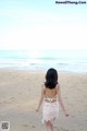 A woman walking on the beach in a white dress.