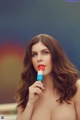 A woman holding a popsicle in front of her face.