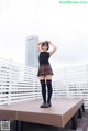A woman in a school uniform standing on a wooden platform.