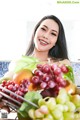 A woman holding a basket full of fruit in a kitchen.