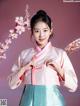 A woman in a pink and blue hanbok posing for a picture.