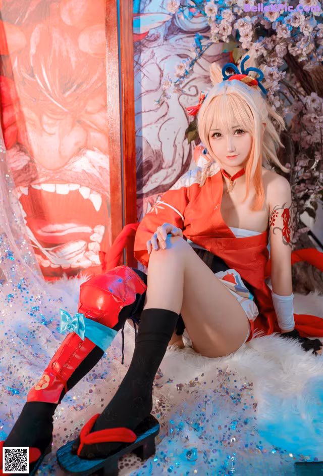 A woman in a red and white outfit sitting on a bed.