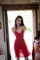 A woman in a red dress standing in front of a door.