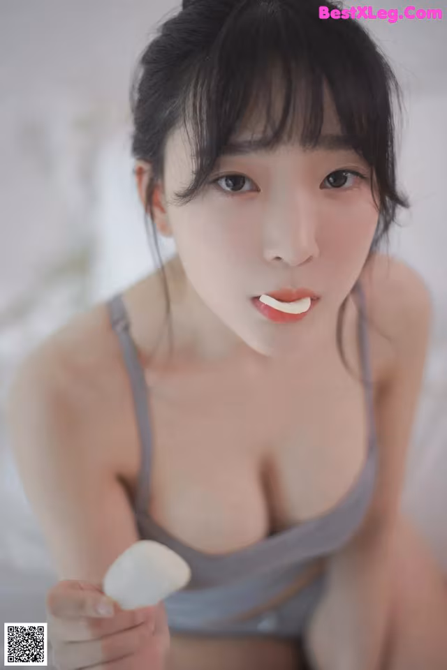 A woman in a gray tank top holding a white object.