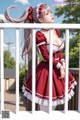 A woman in a red and white dress standing on a balcony.