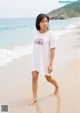 A woman standing on a beach next to the ocean.