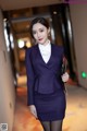 A woman in a purple suit is posing for a picture.