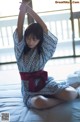 A woman sitting on a bed with her arms outstretched.